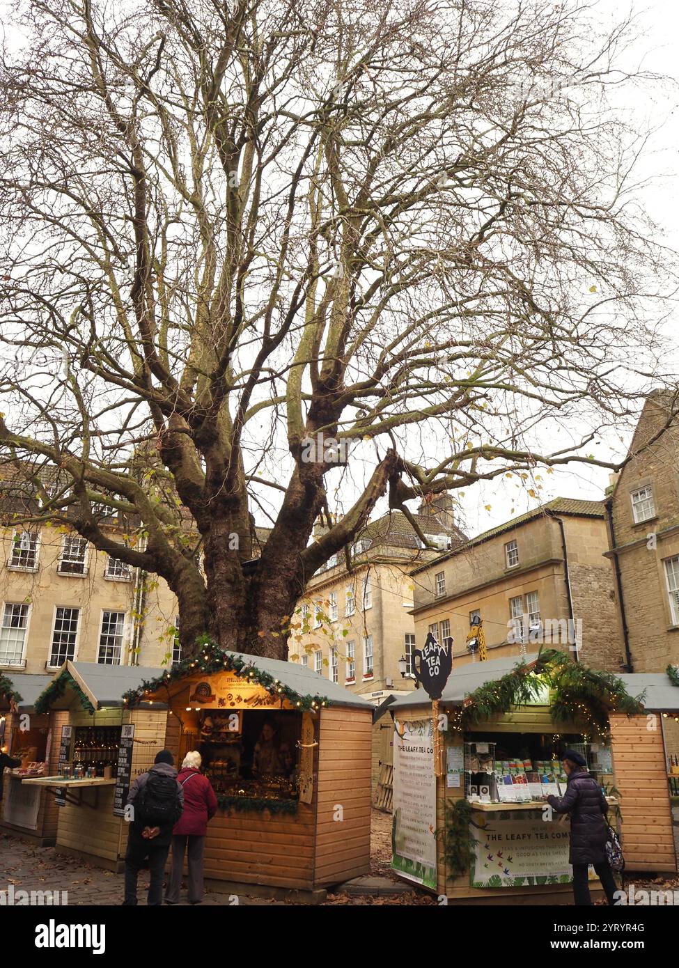 Stands de nourriture de rue sous l'ancien platane à Abbey Green au marché de Noël de Bath, Bath, Somerset vendant des cadeaux de Noël artisanaux et des cadeaux Banque D'Images