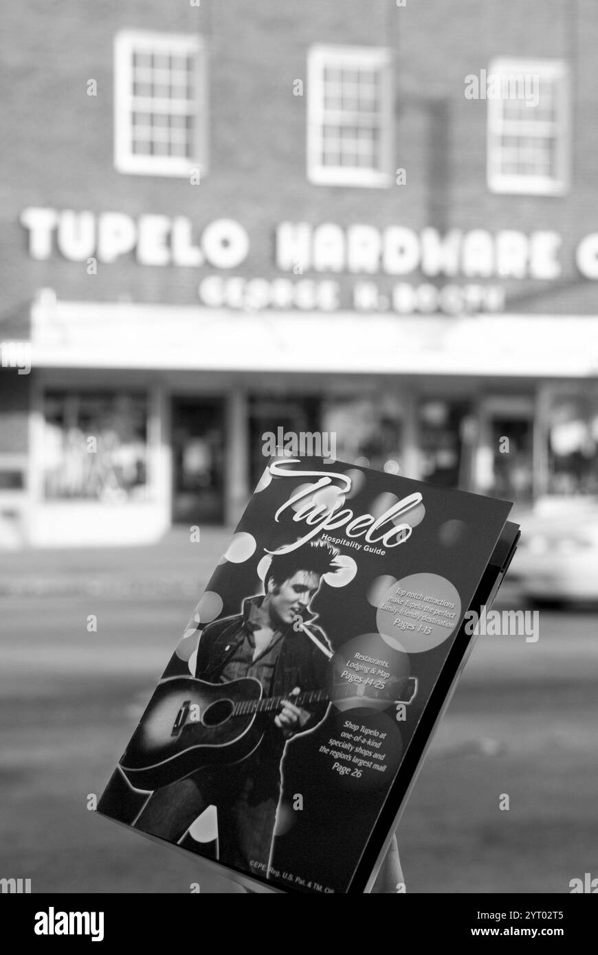 Gros plan d'une brochure de voyage faisant la promotion de Tupelo, Mississippi, avec l'emblématique quincaillerie Tupelo floue en arrière-plan. Banque D'Images