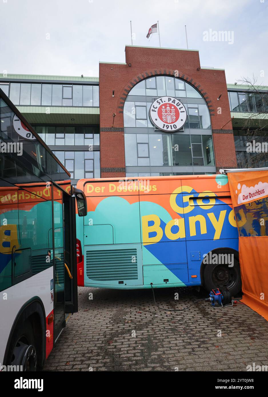 Hambourg, Allemagne. 05th Dec, 2024. Le bus de douche GoBanyo et un bus de Hamburger Hochbahn AG se tiennent devant le club-House du FC lors d’un événement médiatique pour remettre le deuxième bus de douche à l’organisation caritative GoBanyo. Hamburger Hochbahn AG fait don d’un deuxième bus à l’organisation à but non lucratif GoBanyo, qui utilise son bus de douche pour aider les gens dans la rue. Crédit : Christian Charisius/dpa/Alamy Live News Banque D'Images