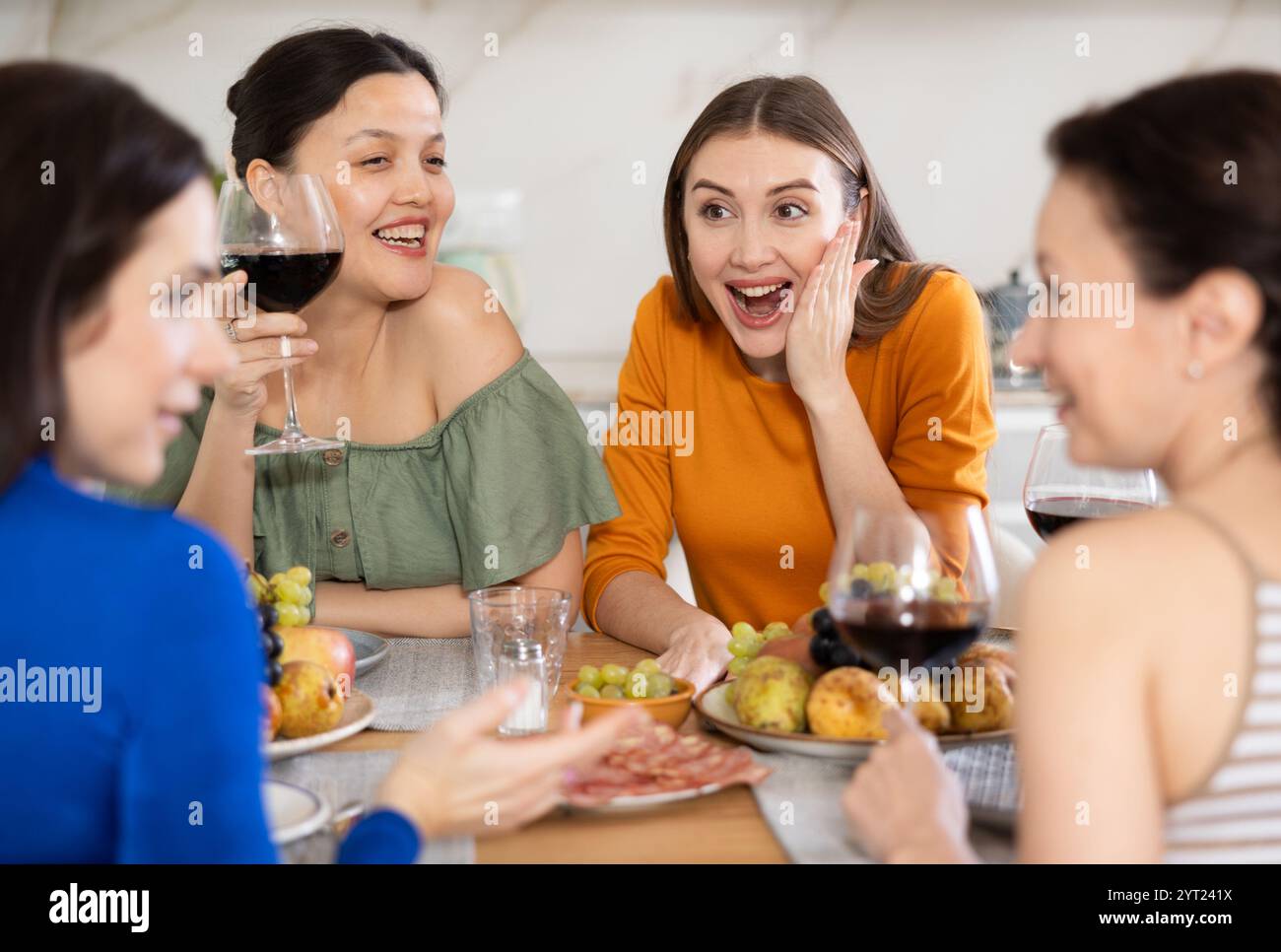 Des femmes heureuses se sont rassemblées autour d'une table festive ; participant à des discussions animées et appréciant les délices du vin Banque D'Images