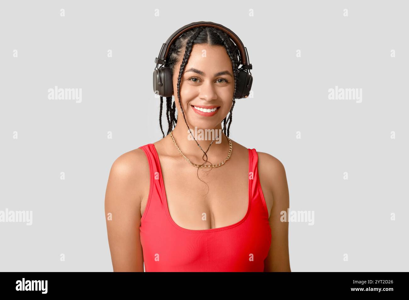 Élégante jeune femme afro-américaine dans des écouteurs avec des dreadlocks sur fond gris Banque D'Images