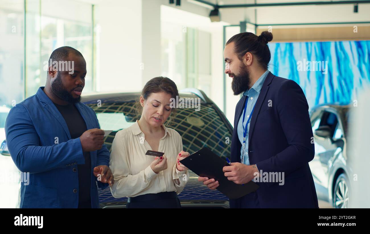 Vendeur de concession automobile offrant des cartes de visite aux clients après avoir négocié les prix des véhicules, en attendant la réponse finale. Agent donnant des cartes de visite aux clients, attendant leur appel, caméra A. Banque D'Images