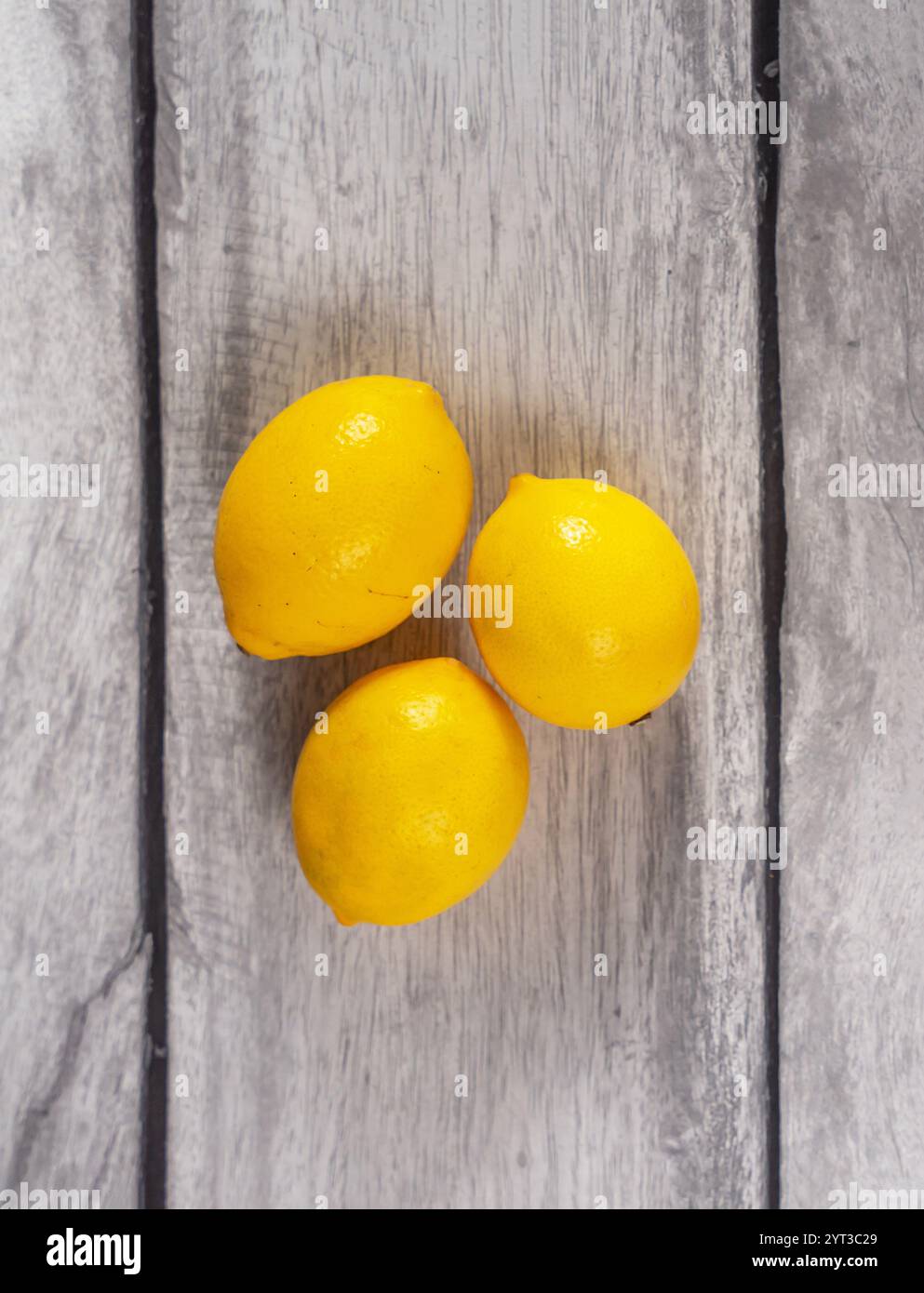 Un plan vertical de trois citrons sur une table en bois gris. Banque D'Images