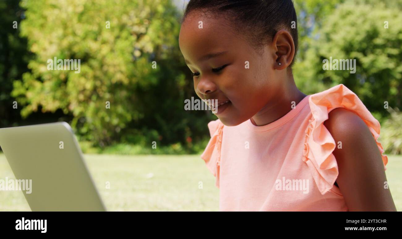 Petite fille utilisant un ordinateur portable dans un parc Banque D'Images