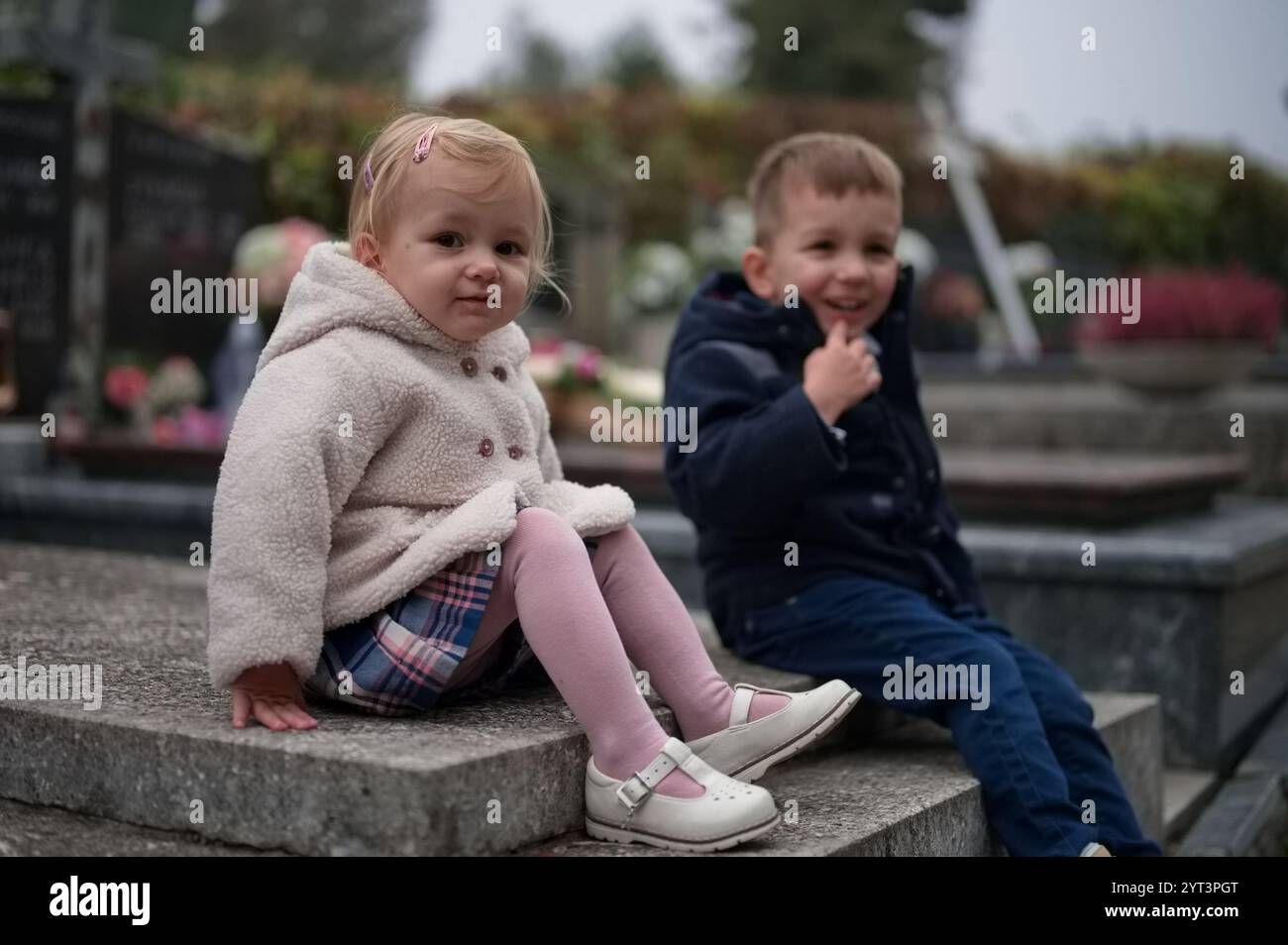 Petit frère et petite sœur assis sur une tombe Banque D'Images