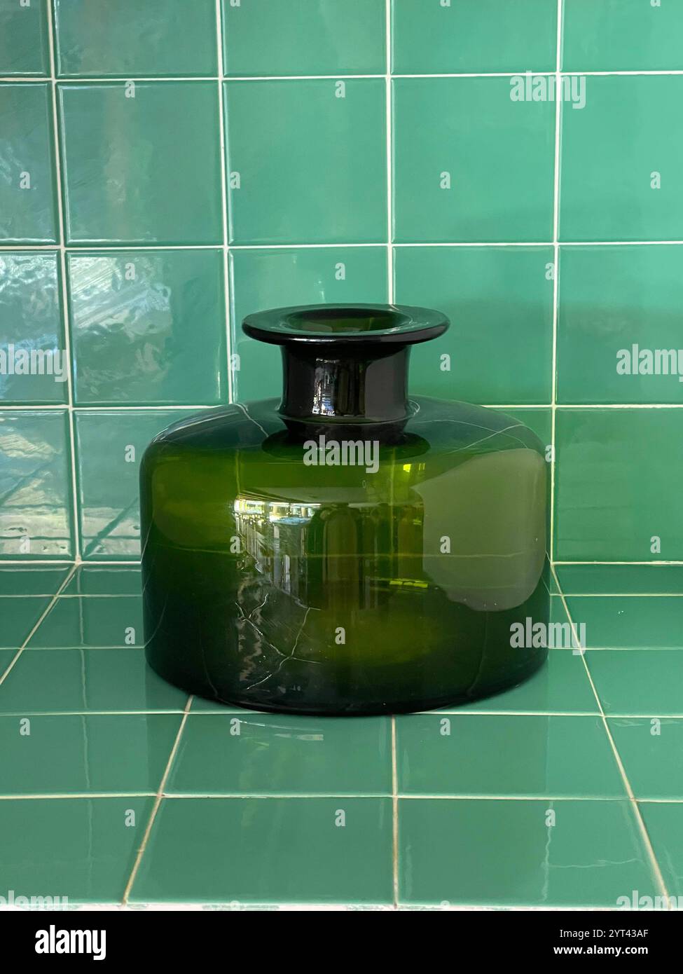 Vase en verre vert sur la surface des carreaux verts. Banque D'Images