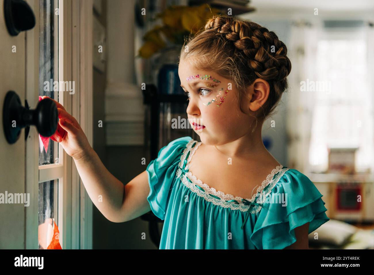Fille dans la robe sarcelle avec le maquillage de paillettes place coeur sur la fenêtre Banque D'Images