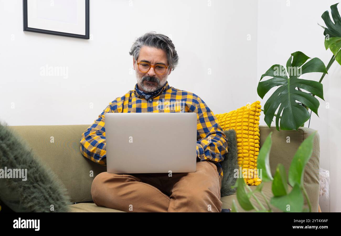 Homme utilisant un ordinateur portable assis dans son salon Banque D'Images