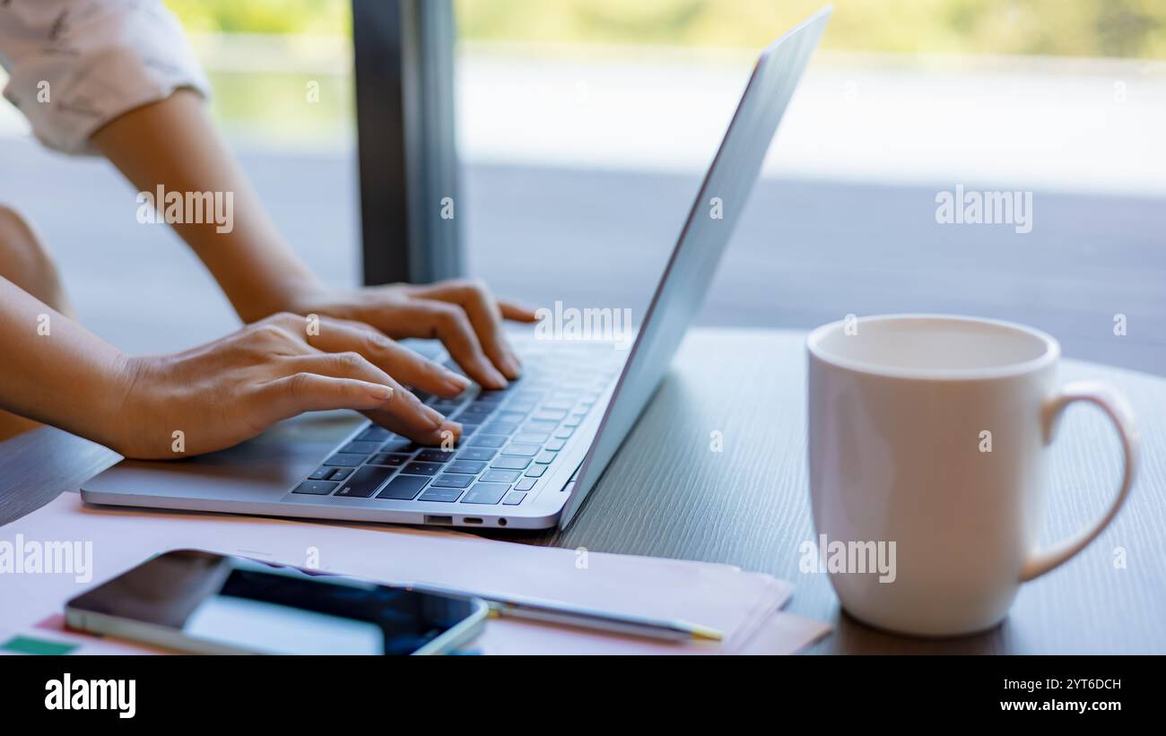 Mains féminines tapant sur le clavier d'ordinateur portable sur le bureau en bois au bureau, technologie, concept d'affaires. Femme d'affaires analyser le graphique de l'entreprise Banque D'Images