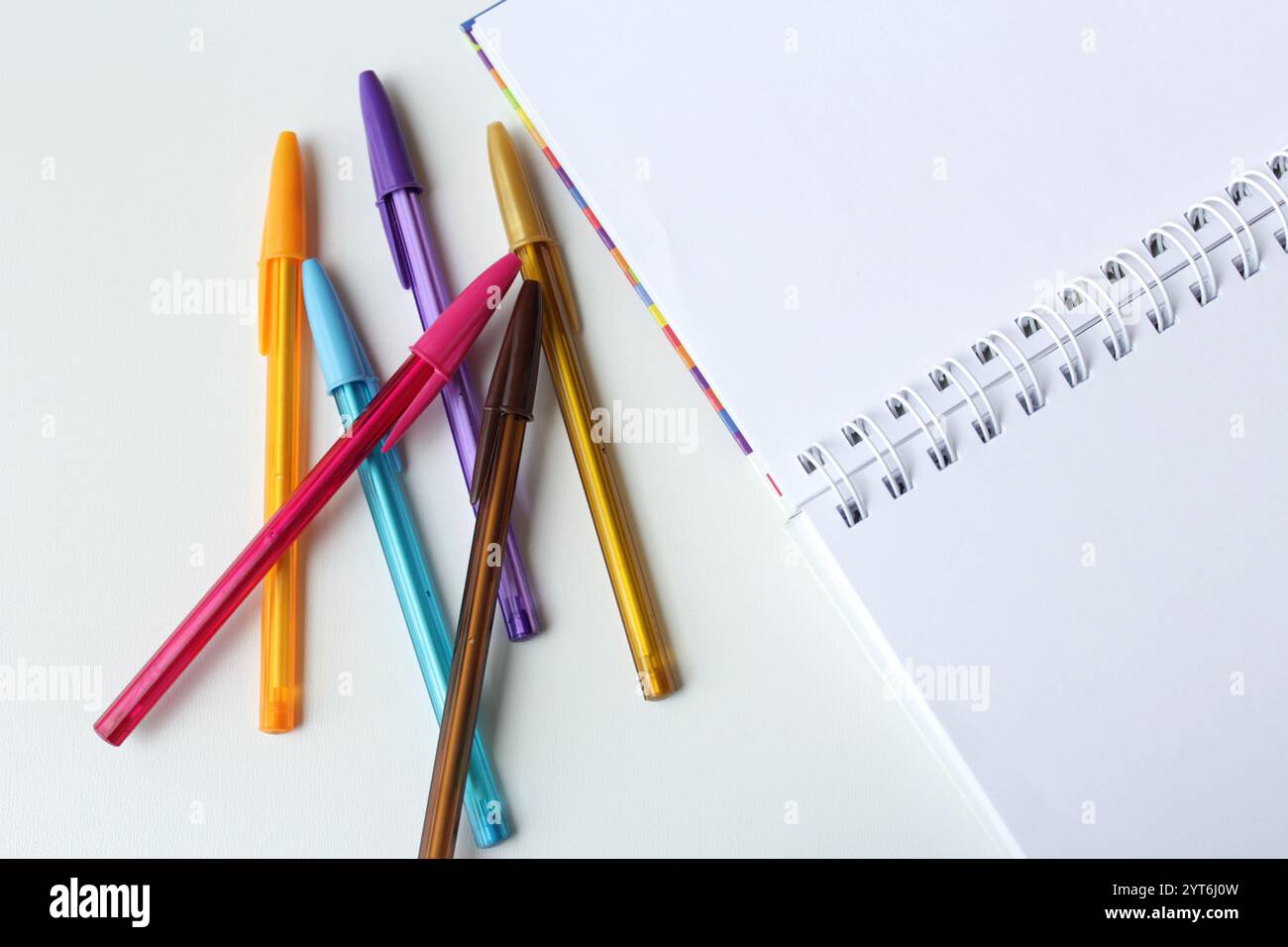 Bouquet de stylos à bille colorés à côté d'un carnet de pages blanches en spirale. Concept de créativité pour l'école, la classe d'art et la leçon de dessin. Banque D'Images