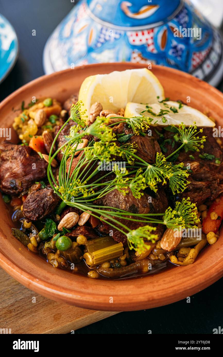 Tajine marocain traditionnel avec agneau, légumes et noix servi avec une salade fraîche. Met en évidence les saveurs méditerranéennes vibrantes et culinaires Banque D'Images