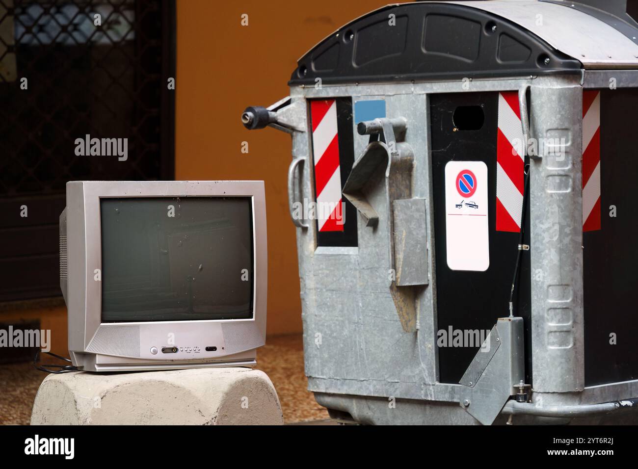 Télévision jetée placée à côté d'un bac de recyclage dans une ville Banque D'Images