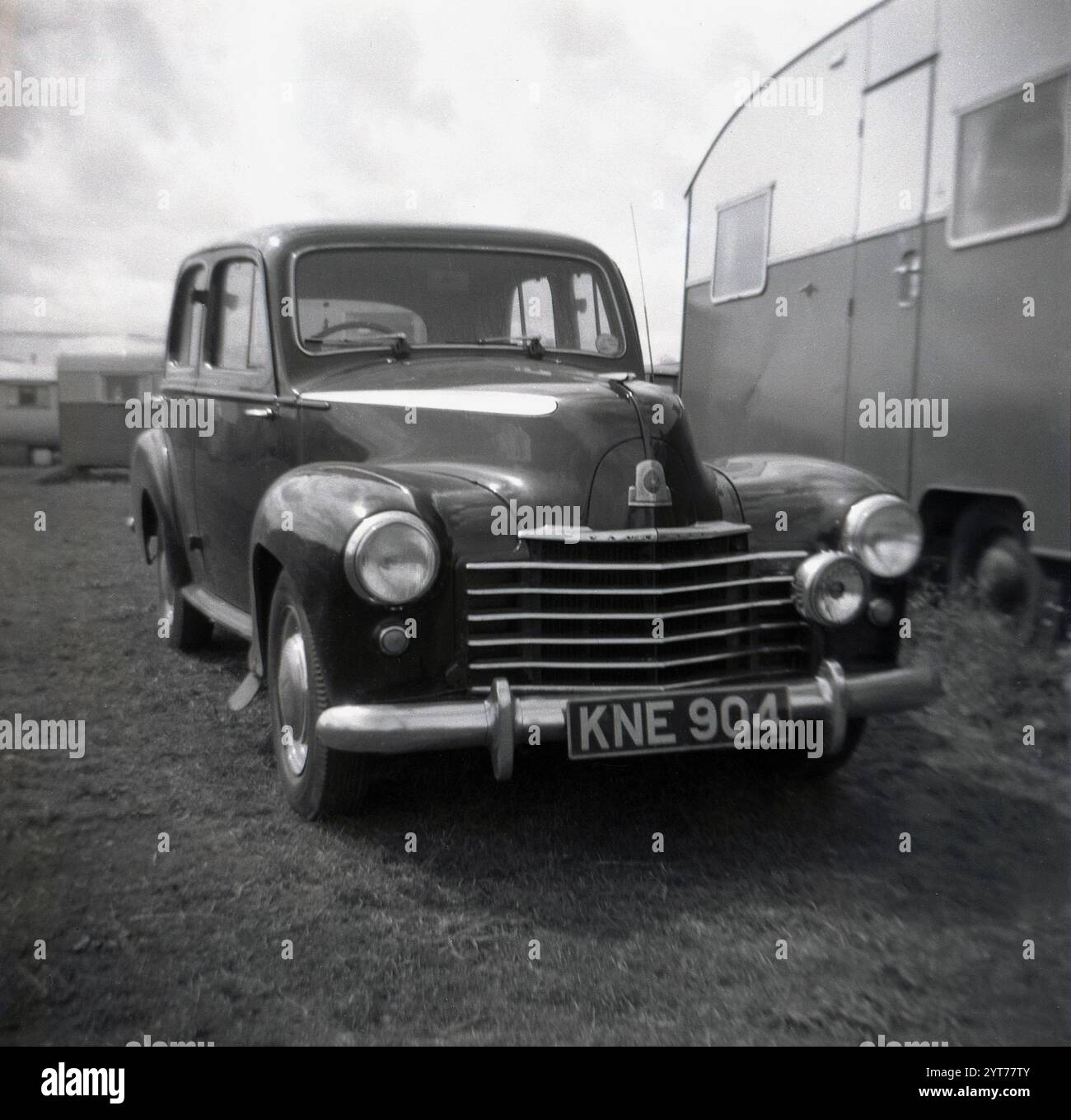 Années 1950, historique, automobile de l'époque (plaque d'immatriculation KNE 904) - un Vauxhall Velox LIP- garé à côté d'une caravane de vacances, Angleterre, Royaume-Uni. La Velox était une berline quatre portes sortie après la seconde Guerre mondiale en 1948 et partageait un corps avec la Vauxhall Wyvren. Le design de la carrosserie des voitures a été inspiré de celui des voitures d'Amérique du Nord. Banque D'Images