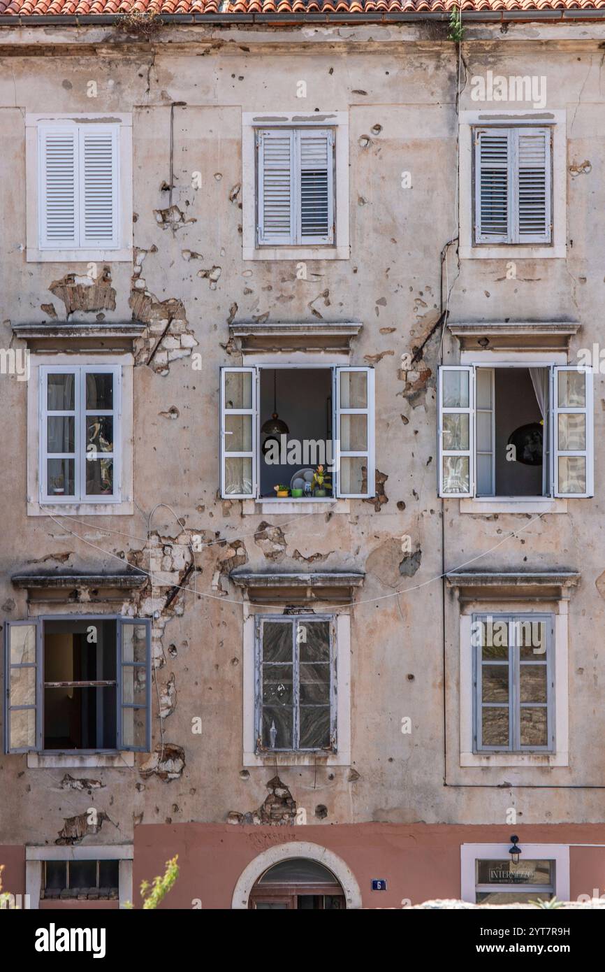 Fenêtre d'un ancien bâtiment avec des trous de balles de la guerre des Balkans. Façade de fenêtre ou façade de maison dans la vieille ville historique de Zadar, mer Adriatique, Dalmatie, Croatie Banque D'Images