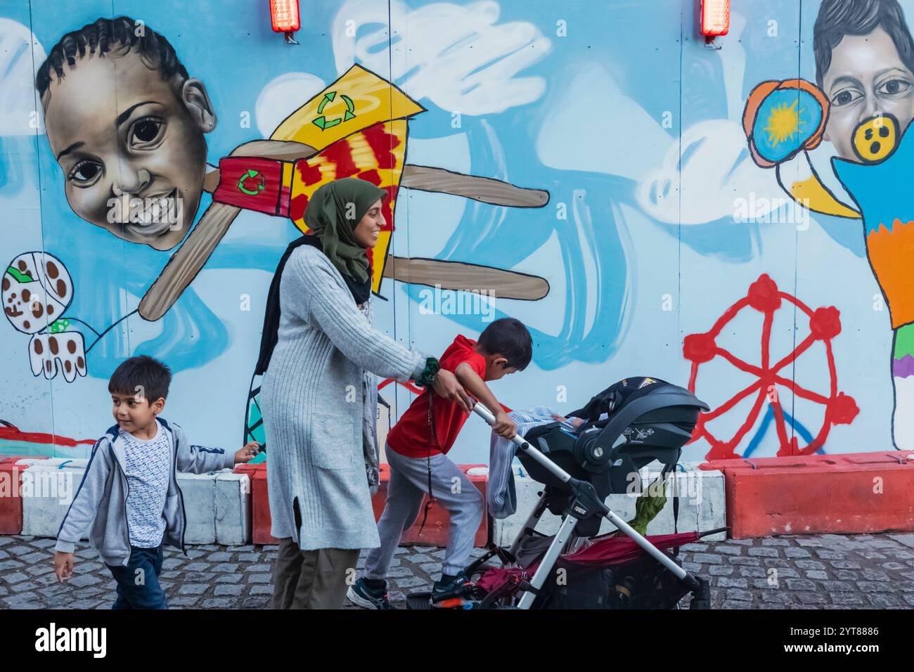 Angleterre, Londres, Southwark, Muslim Lady avec des enfants marchant devant le panneau d'affichage coloré Banque D'Images