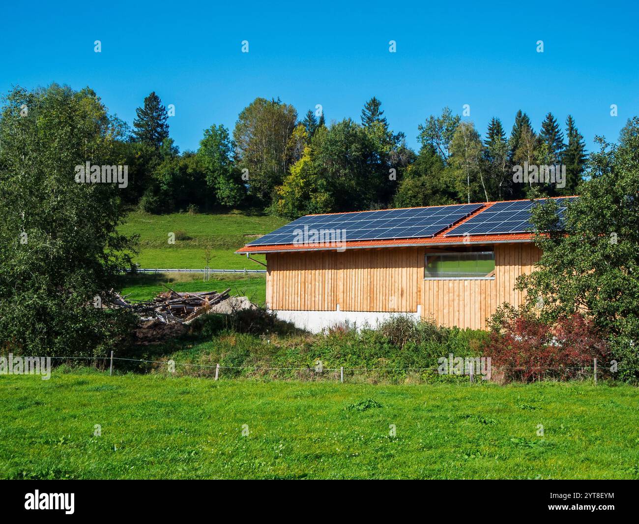 Vue sur un toit de grange couvert de panneaux photovoltaïques en Bavière en été. Banque D'Images