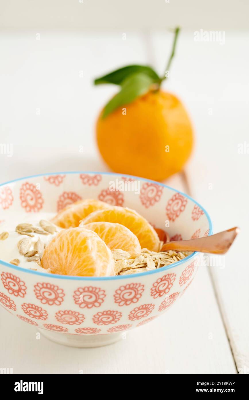 Petit déjeuner muesli avec flocons d'avoine, yaourt et mandarines dans un bol avec une cuillère Banque D'Images