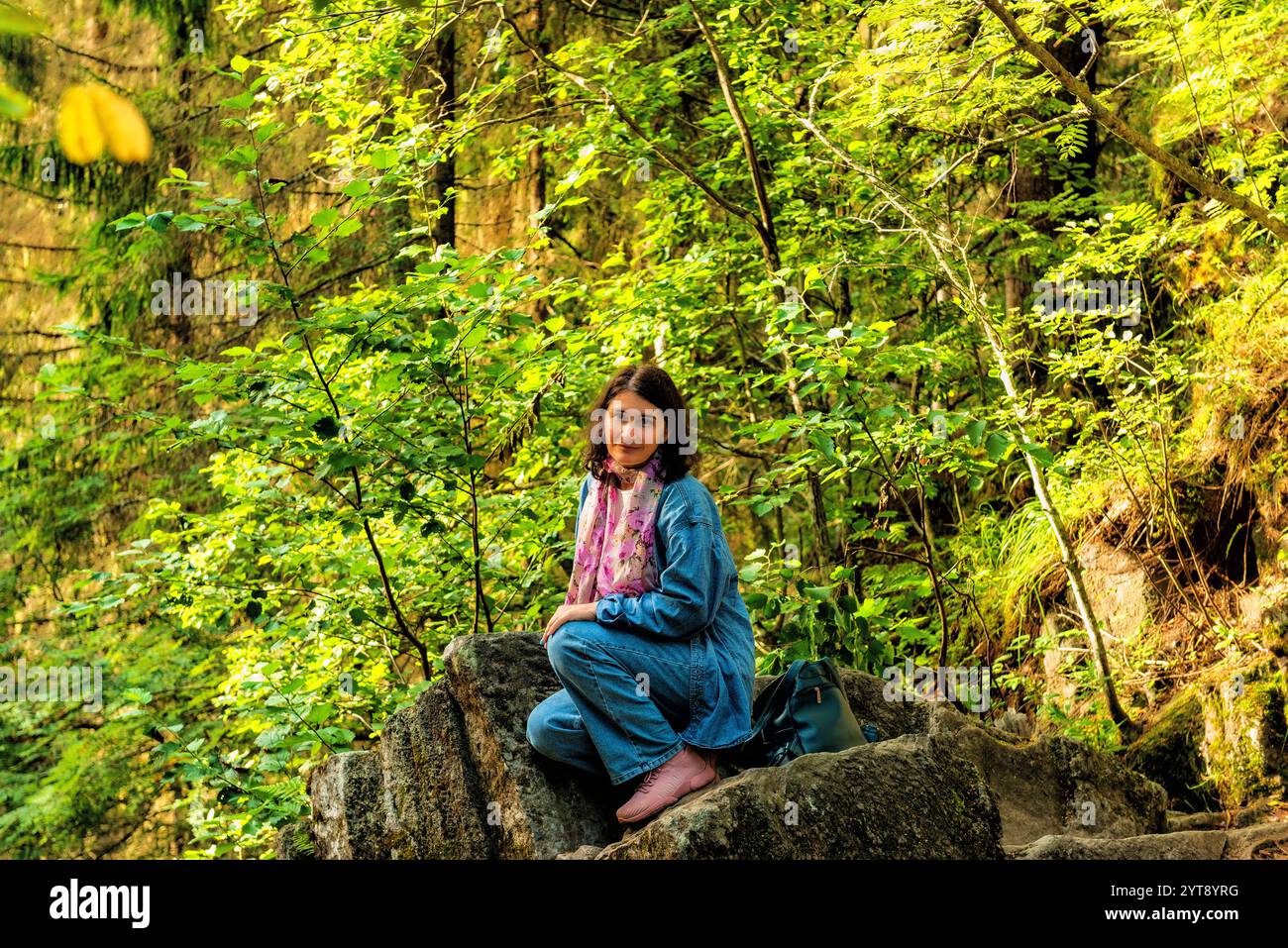 Portrait d'une jeune femme assise sur un rocher et regardant la caméra Banque D'Images