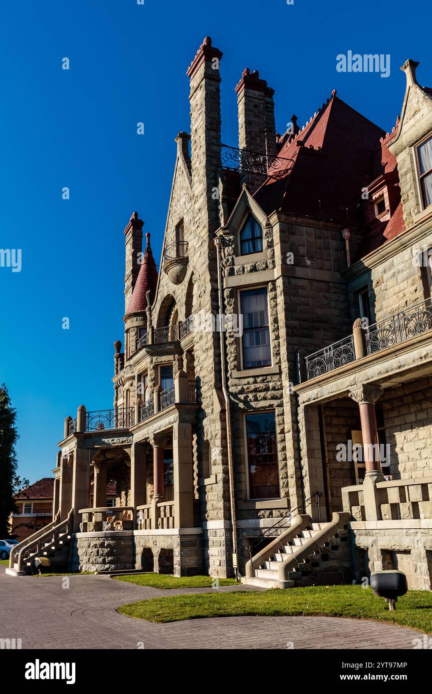 Un grand bâtiment en pierre avec un toit rouge et un ciel bleu en arrière-plan. Le bâtiment a beaucoup de fenêtres et un balcon Banque D'Images