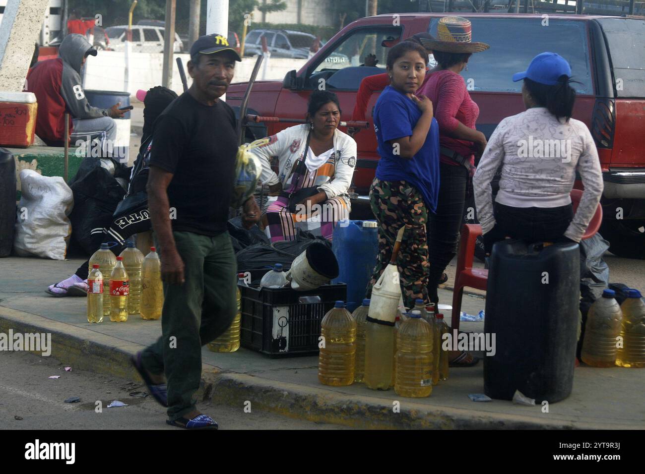 Venezuela-Paraguachón-6-12-2024. Les gens vendent de l'essence colombienne de contrebande, à trente mètres du poste de contrôle de la Garde nationale bolivarienne (GNB), ce vendredi 6 décembre, dans le secteur de la Raya à Paraguachón, dans l'État de Zulia, Venezuela. Les nouvelles mesures de sécurité ordonnées par le président Nicolás Maduro au poste de contrôle de Paraguachón, situé à huit kilomètres de la frontière entre le Venezuela et la Colombie, visent à renforcer la sécurité et à « progresser dans la lutte contre la contrebande et la violence dans la zone frontalière ». (Photo Humberto Matheus/Sipa USA) Banque D'Images