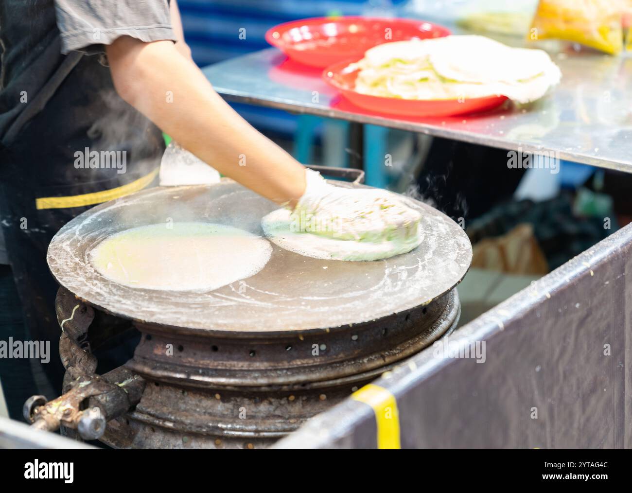 Un homme applique la pâte roti sur la poêle chaude pour faire roti dans le marché de la nourriture de rue. Banque D'Images