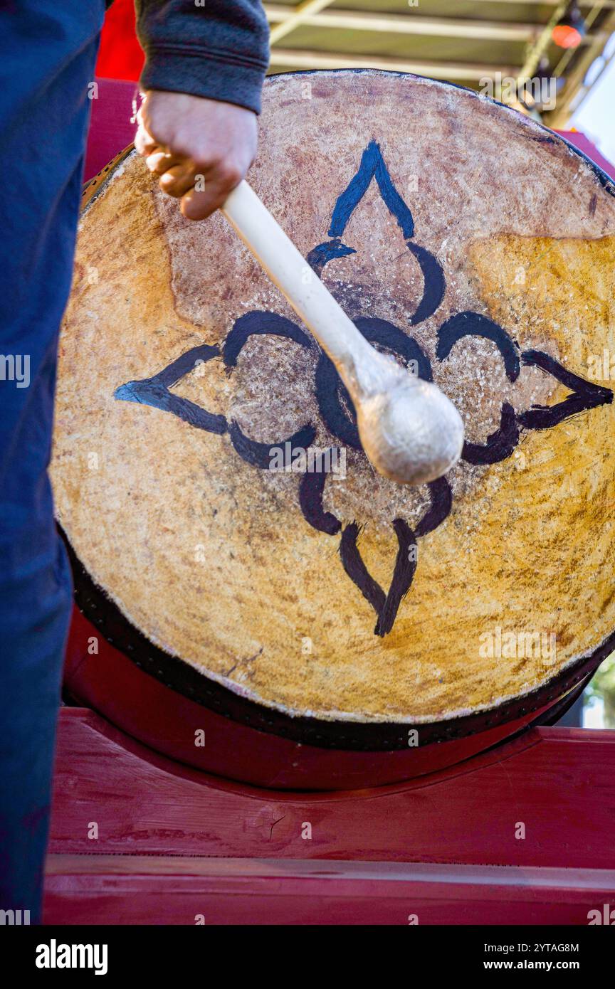 Main avec maillet frappant un tambour avec un motif de fleur lors d'un événement Têt (nouvel an lunaire). Têt est la célébration la plus importante dans la culture vietnamienne. Banque D'Images