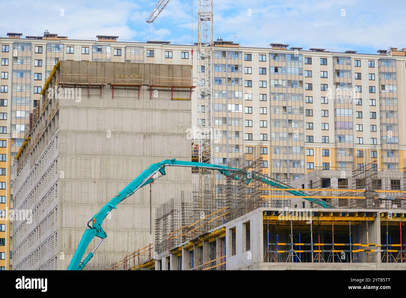 Couler des planchers de ciment d'un bâtiment résidentiel à plusieurs étages en construction à l'aide d'un camion de pompe à béton avec flèche élevée pour fournir le mélange à l'uppe Banque D'Images