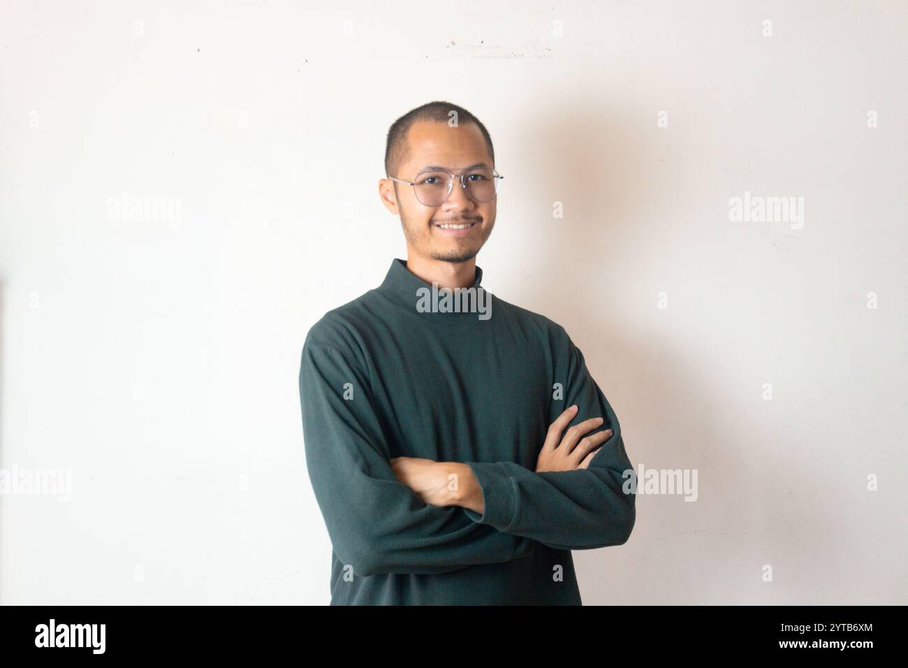 Jeunes hommes portant un pull et des lunettes de vue bras croisé souriant sur fond blanc isolé Banque D'Images