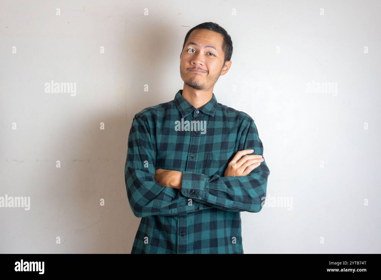 Jeunes hommes portant le bras croisé en flanelle verte souriant sur fond blanc isolé Banque D'Images