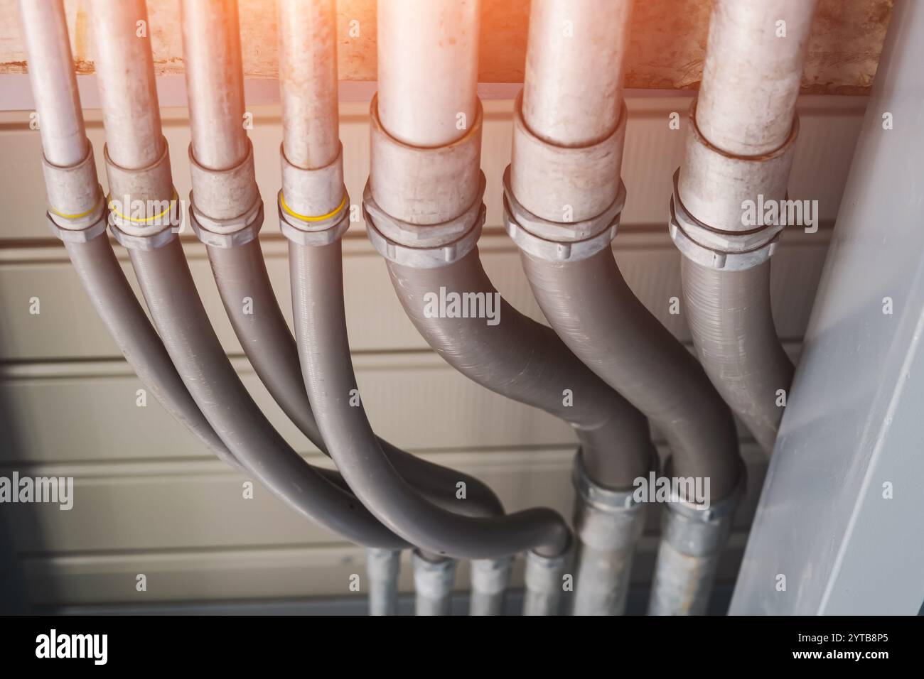 Tuyauterie industrielle au plafond d'un bâtiment, vue aérienne d'un réseau complexe de tuyaux et conduits industriels en caoutchouc installés le long d'un bâtiment Banque D'Images