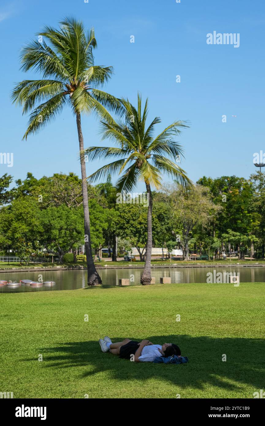 Bangkok, Thaïlande. 06th Dec, 2024. Un étudiant est vu allongé sur le sol d'herbe sur une partie d'ombre, au parc Chatuchak, à Bangkok. Chatuchak Park est un parc public à Bangkok, offrant une retraite paisible avec des espaces verts, un lac et des zones de loisirs loin de l'agitation de la ville. Crédit : SOPA images Limited/Alamy Live News Banque D'Images
