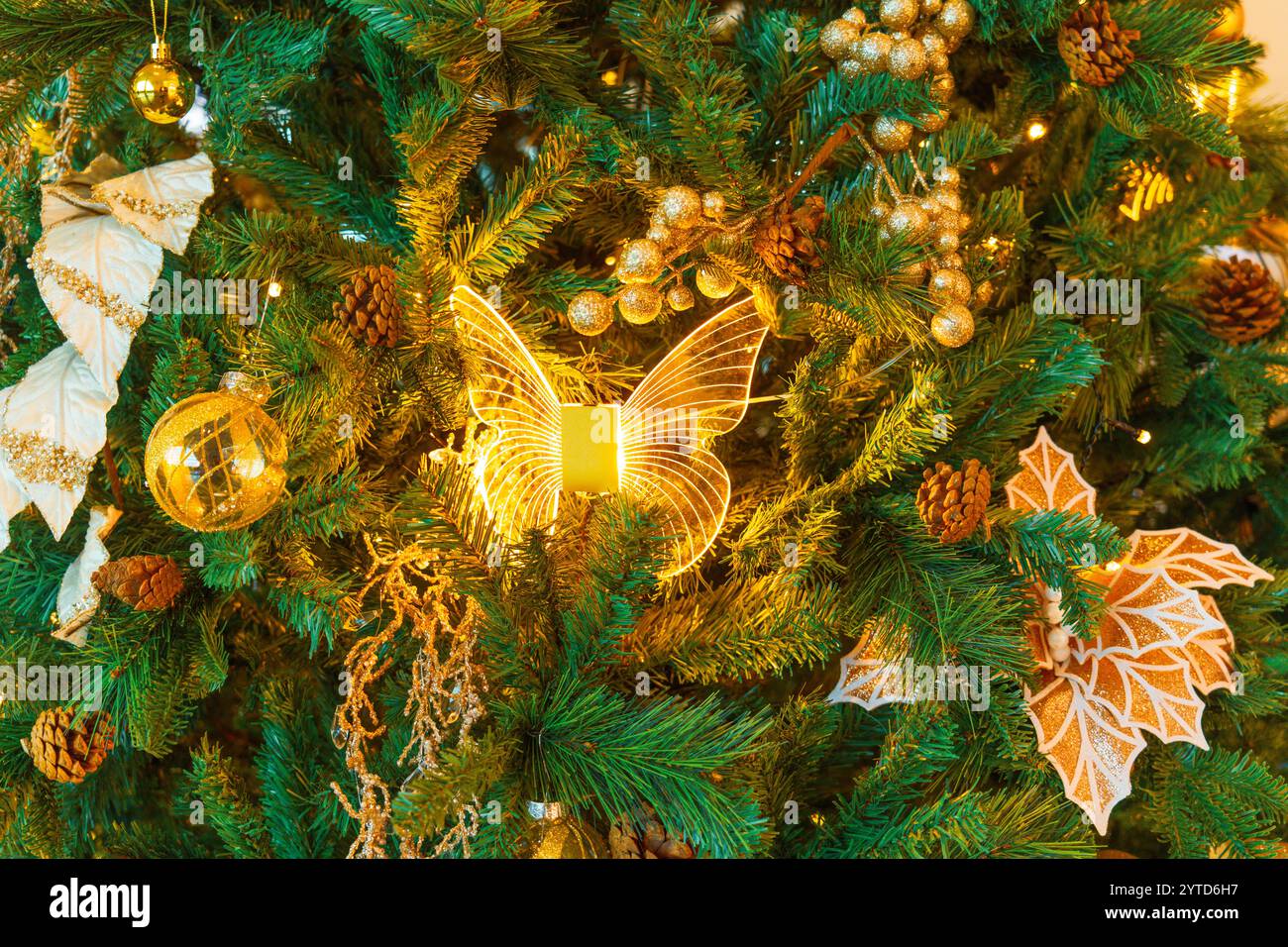 Arbre vert de Noël avec jouets du nouvel an, boules dorées et jaunes, feuilles, papillon. Banque D'Images