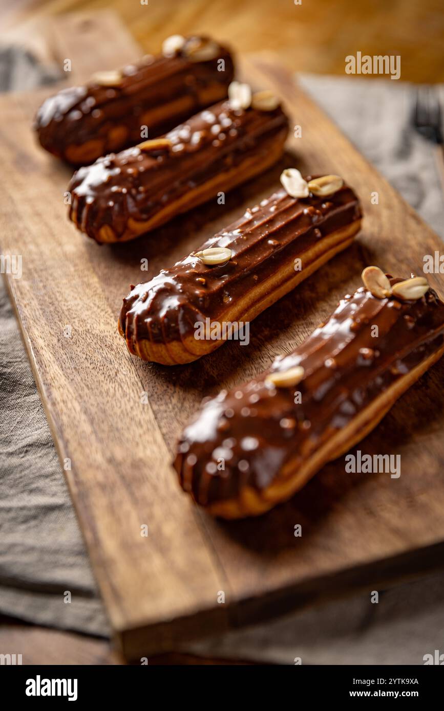 Délicieuses eclairs de chocolat avec des arachides reposant sur une planche de bois Banque D'Images