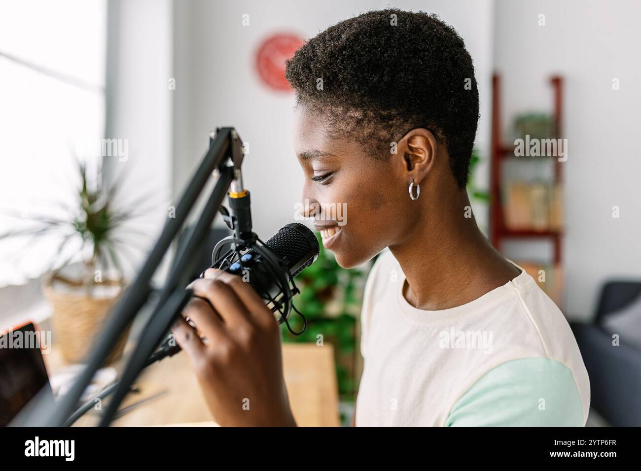 Femme créative noire heureuse enregistrant un podcast à l'aide d'un microphone professionnel Banque D'Images