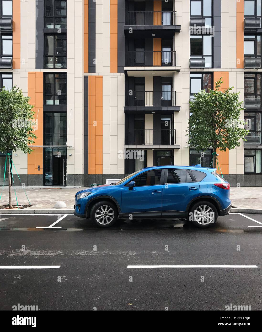 Voiture bleue garée sur une rue en face d'un immeuble résidentiel moderne. Vue de profil latérale du multisegment Mazda CX-5 en milieu urbain. Banque D'Images