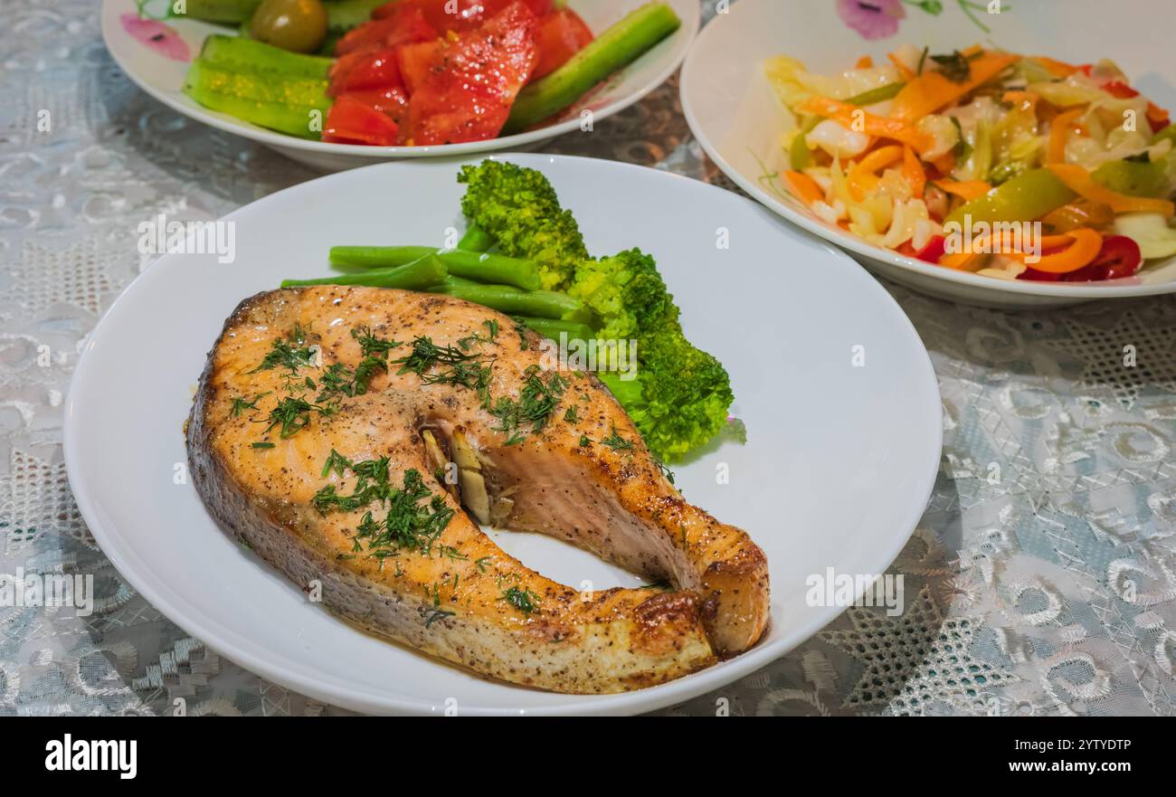Saumon atlantique norvégien cuit au four. Saumon aux herbes et légumes bouillis sur une assiette blanche avec salade et chou aigre. Banque D'Images
