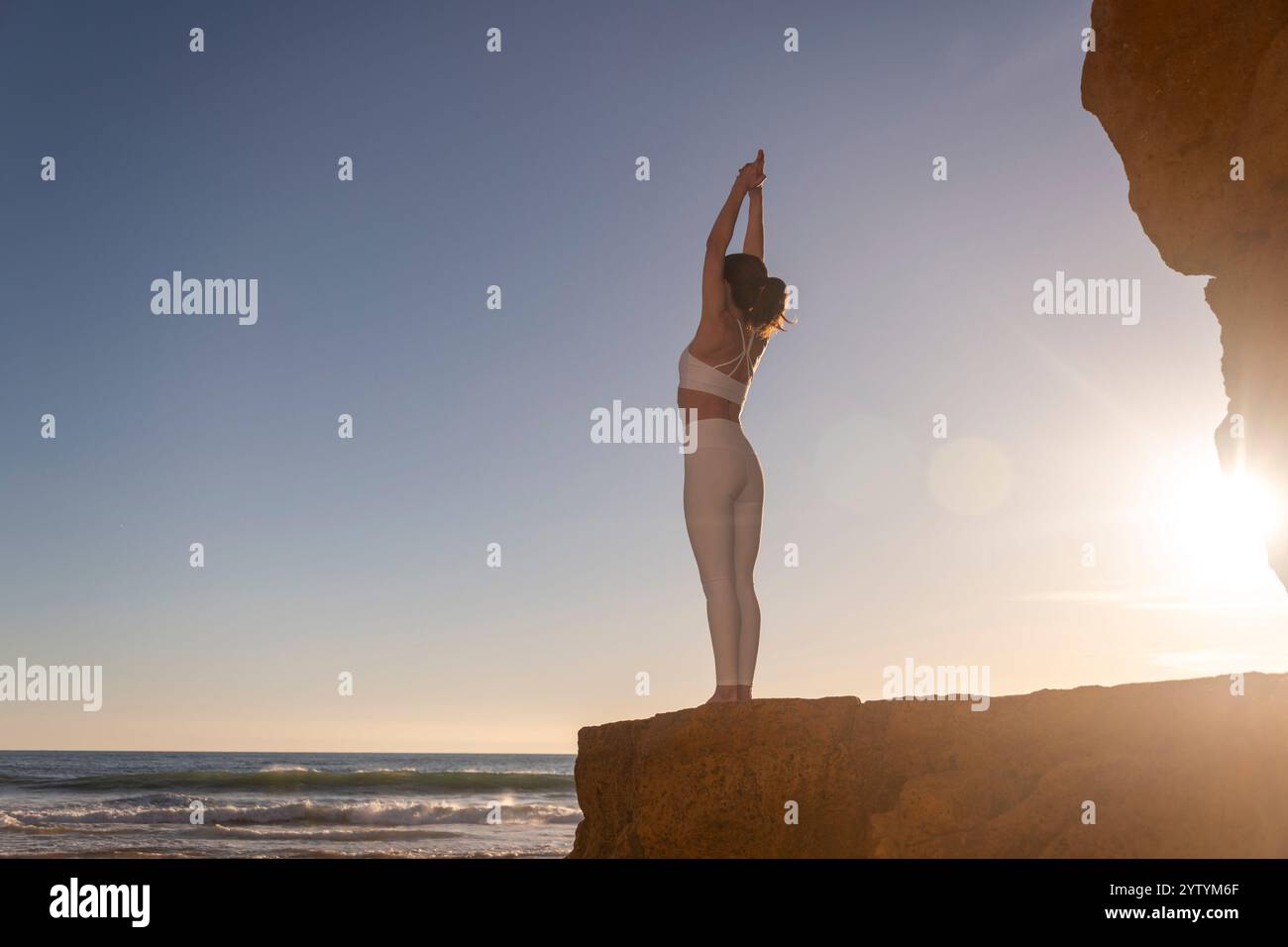 femme sportive debout sur un rocher méditant au lever du soleil, au coucher du soleil Banque D'Images femme sportive debout sur un rocher méditant au lever du soleil, au coucher du soleil Banque D'Images