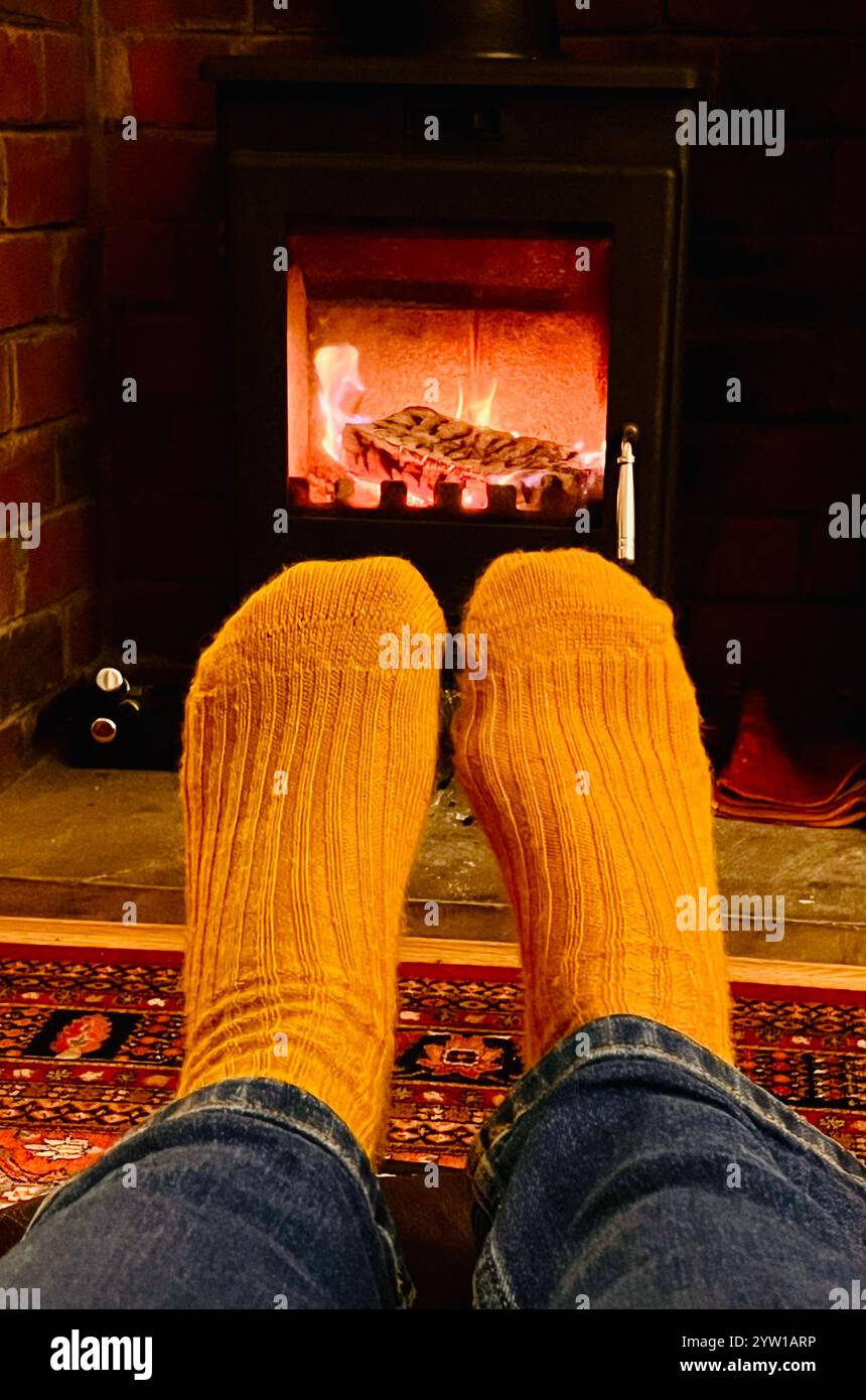 Pieds dans des chaussettes de moutarde devant le poêle à bois Banque D'Images Pieds dans des chaussettes de moutarde devant le poêle à bois Banque D'Images
