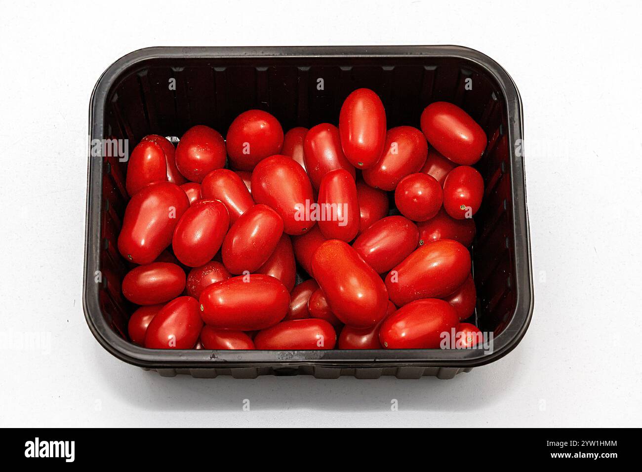 Grande pile de tomates rouges prunes biologiques fraîches à l'intérieur d'une boîte en plastique noire Banque D'Images