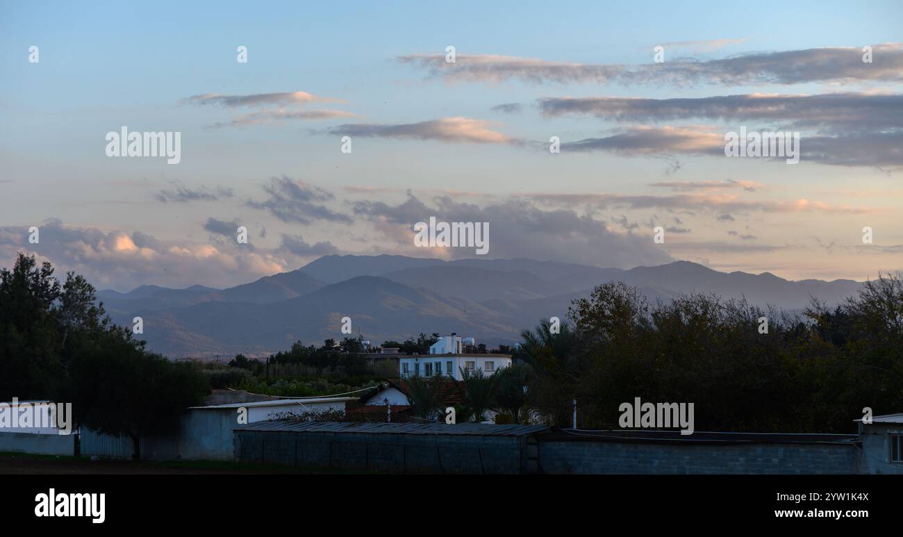 Le crépuscule tombe sur un paysage serein avec des montagnes et des nuages améliorant l'atmosphère enchanteresse de la nature. Banque D'Images