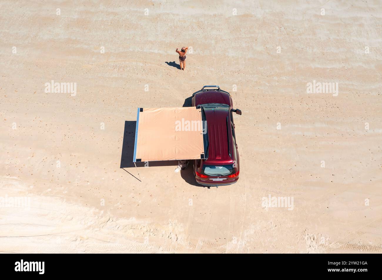 Vue aérienne d'une femme en maillot de bain sur une plage blanche devant un 4x4 avec auvent d'ombre à Moana Beach à Adélaïde, Australie méridionale. Banque D'Images