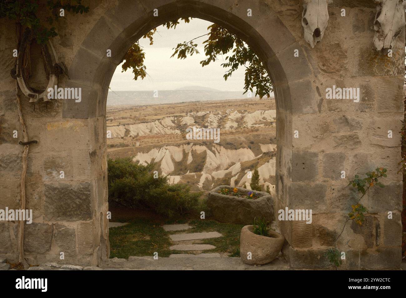 Vue encadrée de la vallée des formations rocheuses pittoresques de Cappadoce à travers une arche en pierre historique Banque D'Images