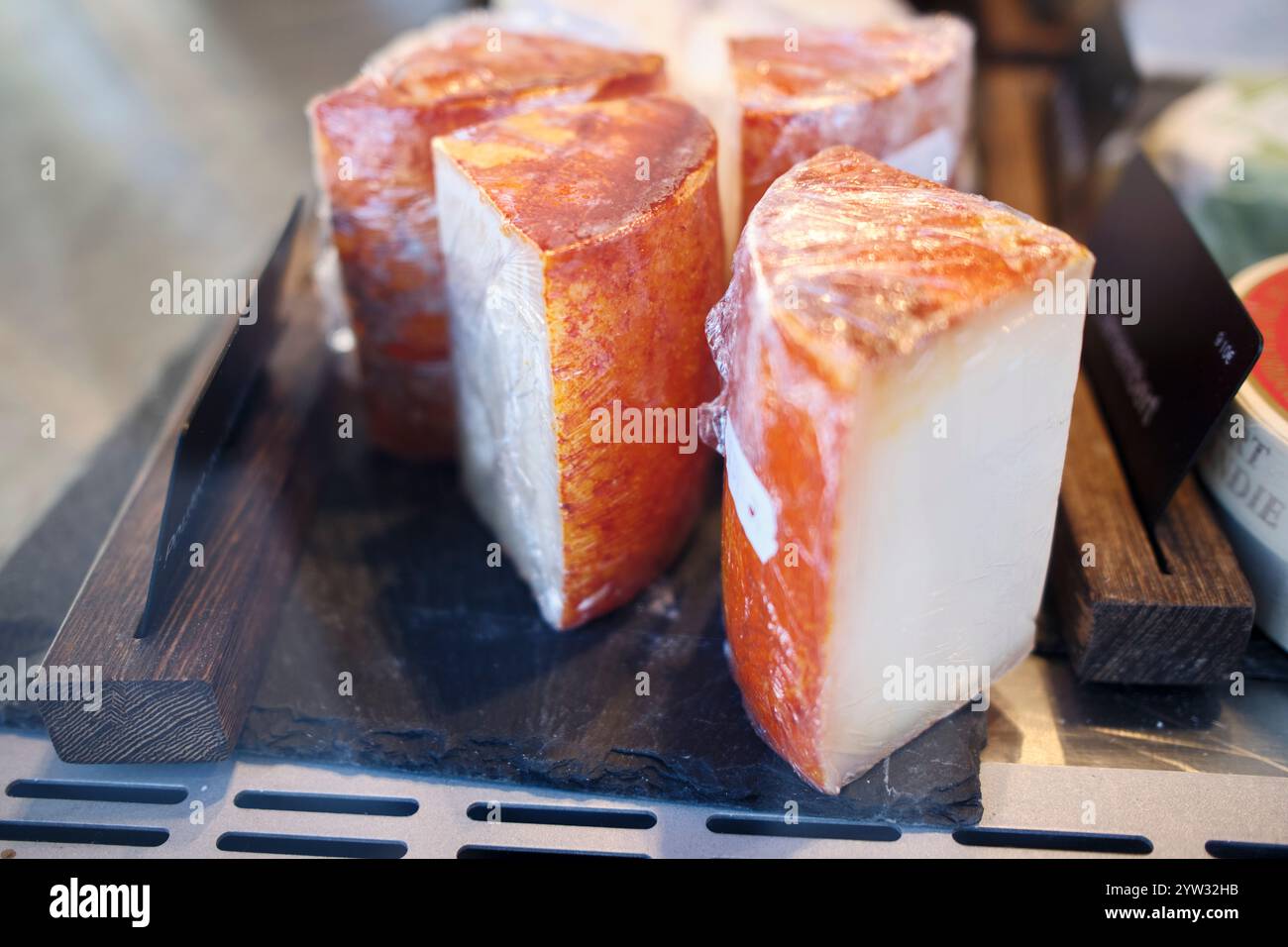 Tranches de fromage artisanales fraîches sur un présentoir en bois. Banque D'Images