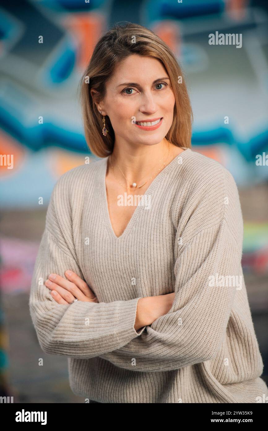 Femme confiante avec les bras croisés souriant devant un mur de graffitis coloré, USA Banque D'Images