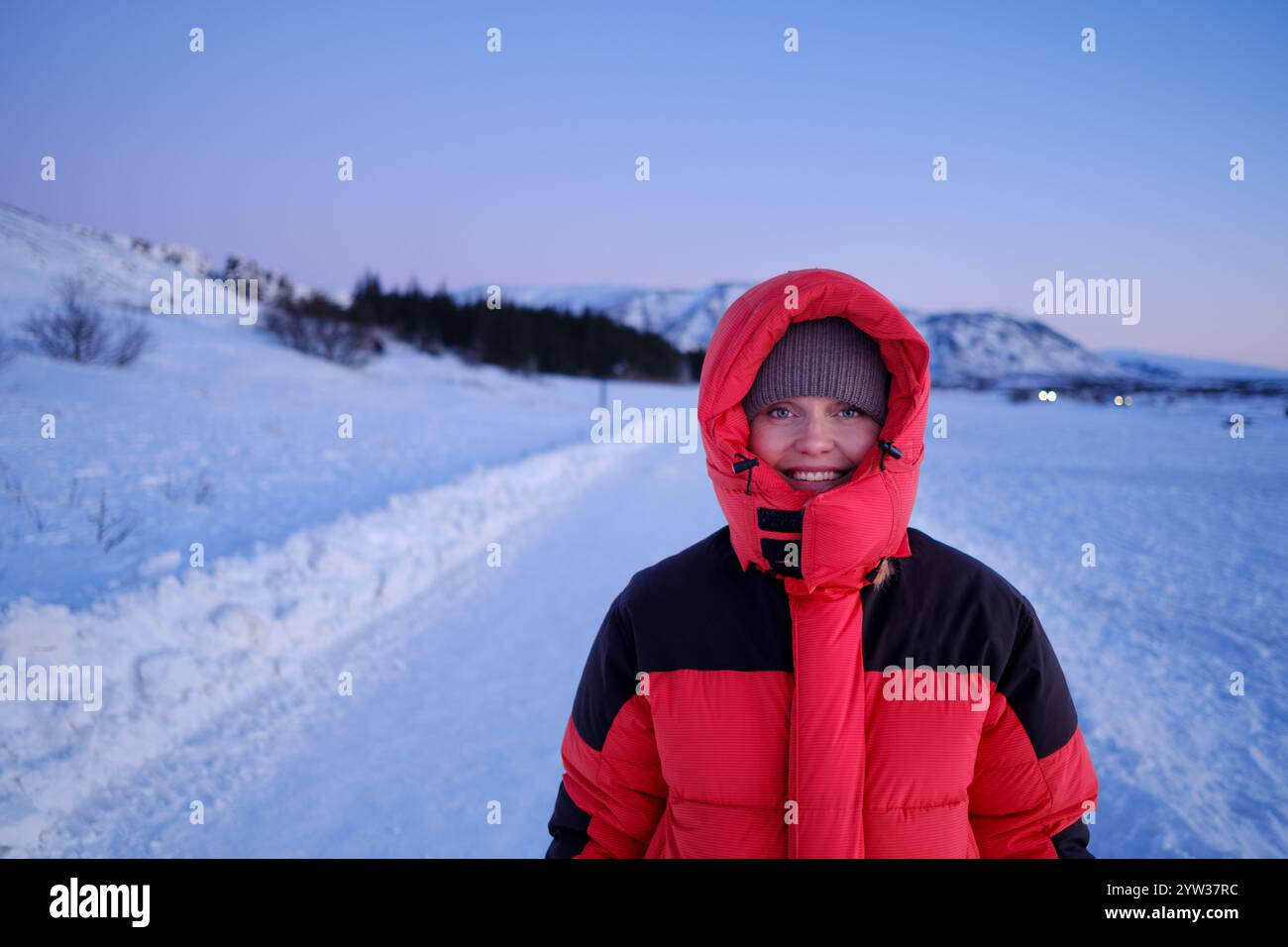 Une femme en manteau rouge dans un paysage enneigé Banque D'Images