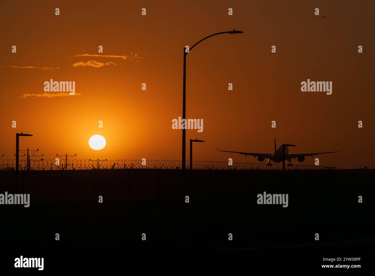 Silhouette d'un avion au départ de l'aéroport LAX Los Angeles au coucher du soleil. Ciel orange. Infrastructure aéroportuaire en silhouette Banque D'Images