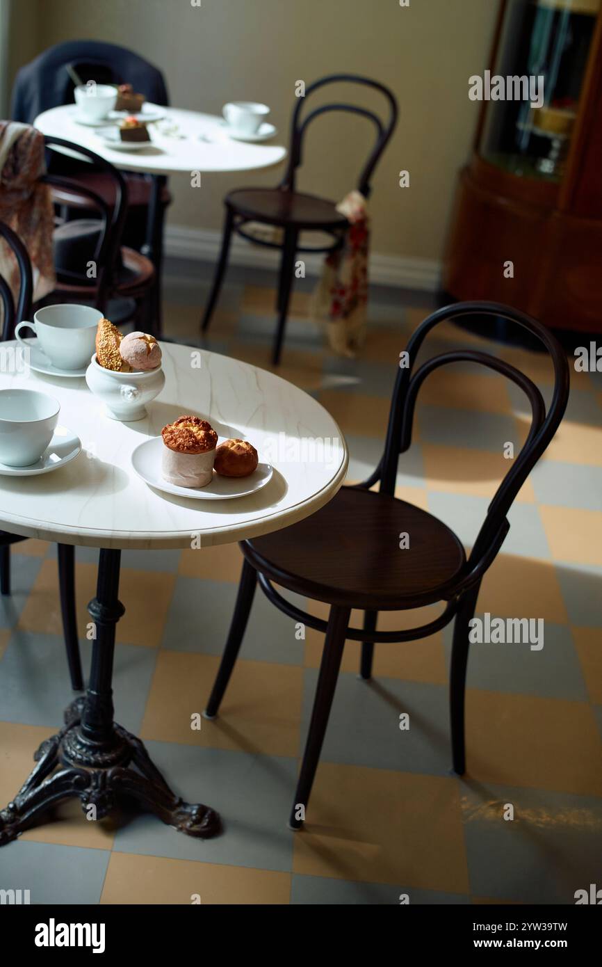 Élégant intérieur de café avec une table en marbre blanc, des chaises noires classiques et des pâtisseries sur une assiette, Trondheim, Norvège Banque D'Images