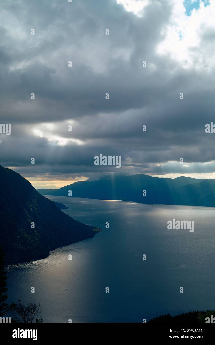 Les rayons du soleil traversent les nuages sur un fjord serein entouré de montagnes, Romsdalfjorden, Norvège Banque D'Images