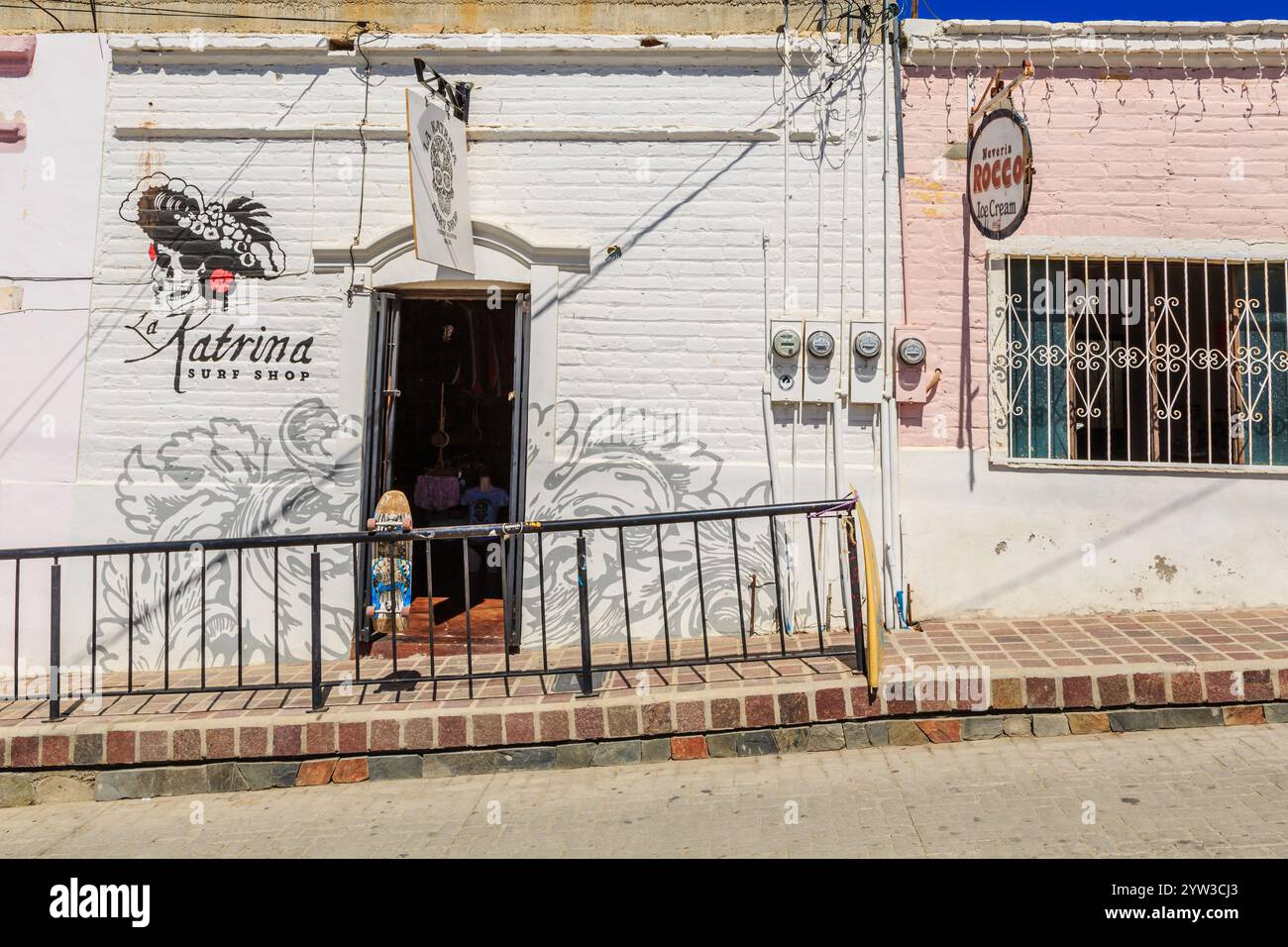 Une petite boutique avec un panneau blanc qui dit 'Katrina Surf Shop' dessus. La boutique est située dans une rue avec un trottoir en briques Banque D'Images