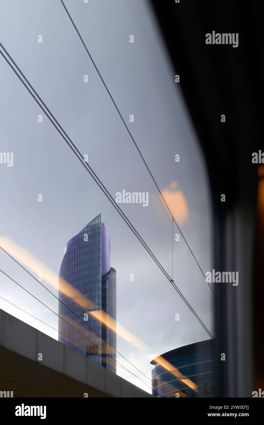 Gratte-ciel vu d'en bas contre un ciel nuageux, avec des lignes architecturales et des câbles croisant le cadre, Bruxelles, Belgique Banque D'Images
